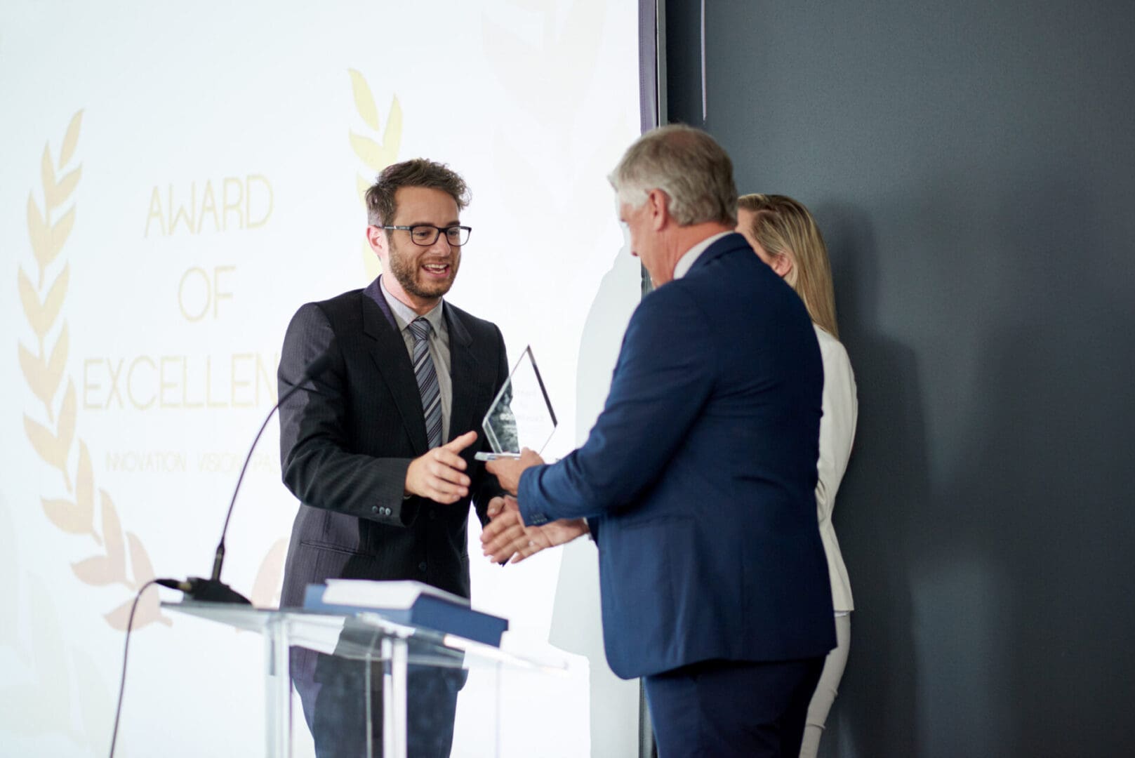 Workplace recognition makes all the difference Man receiving an award on stage handshake.